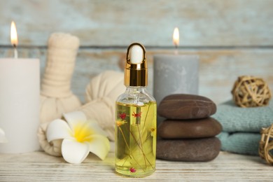 Photo of Bottle with essential oil on white wooden table. Spa product
