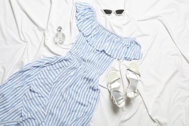 Flat lay composition with stylish light blue dress on white fabric