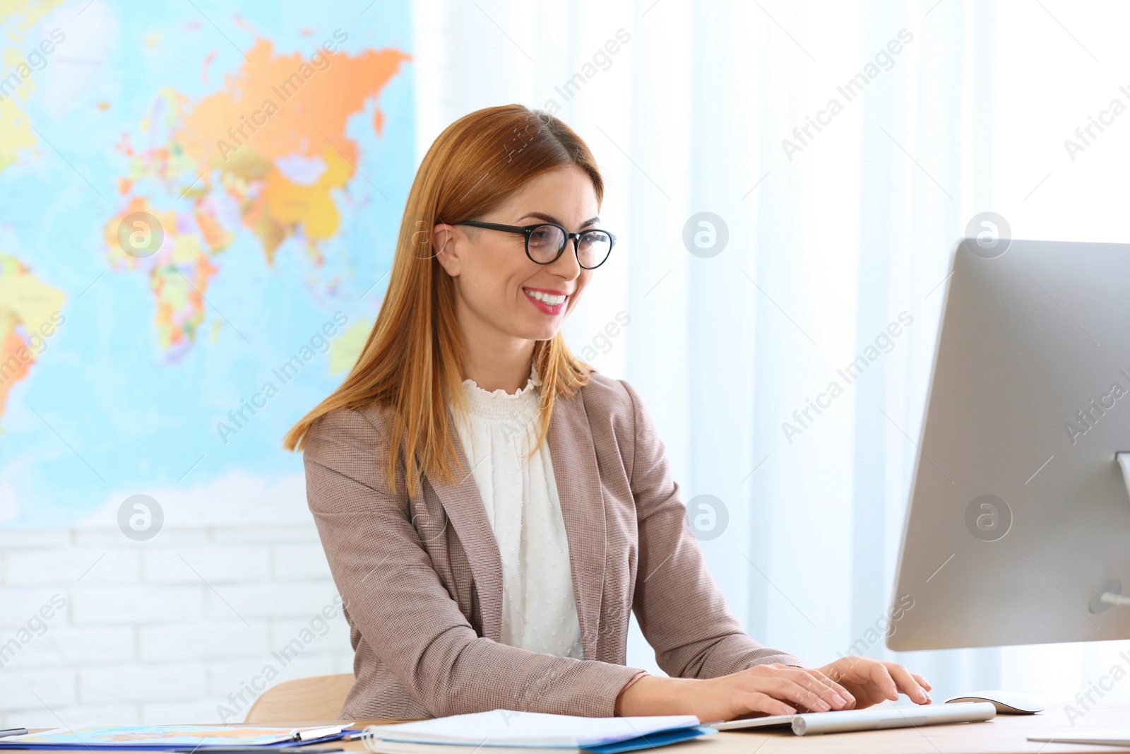 Photo of Beautiful consultant working with computer in travel agency