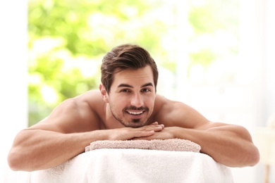 Photo of Handsome young man relaxing on massage table in spa salon