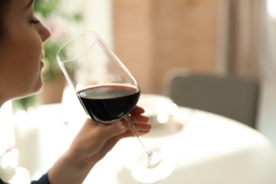 Woman with glass of wine in restaurant, closeup. Space for text