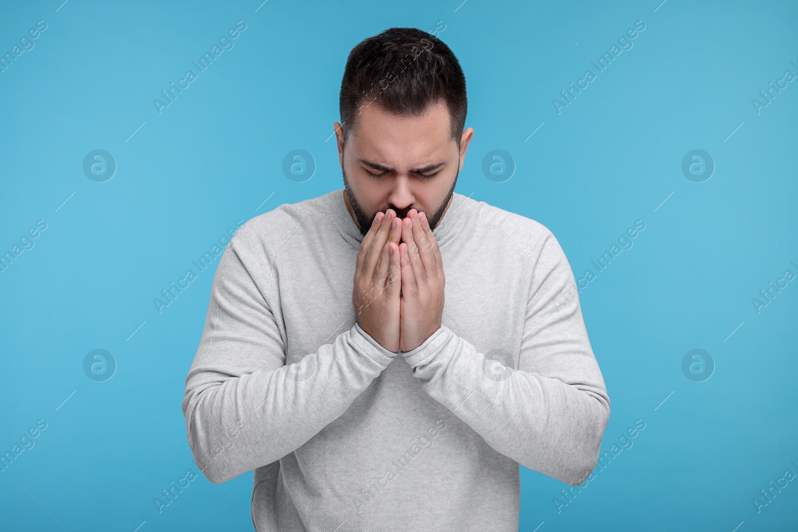 Photo of Sick man coughing on light blue background