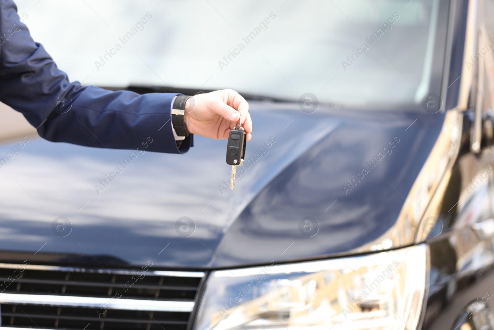 Photo of Man holding key in modern auto dealership, closeup. Buying new car