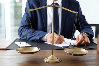 Photo of Scales of justice and blurred lawyer on background