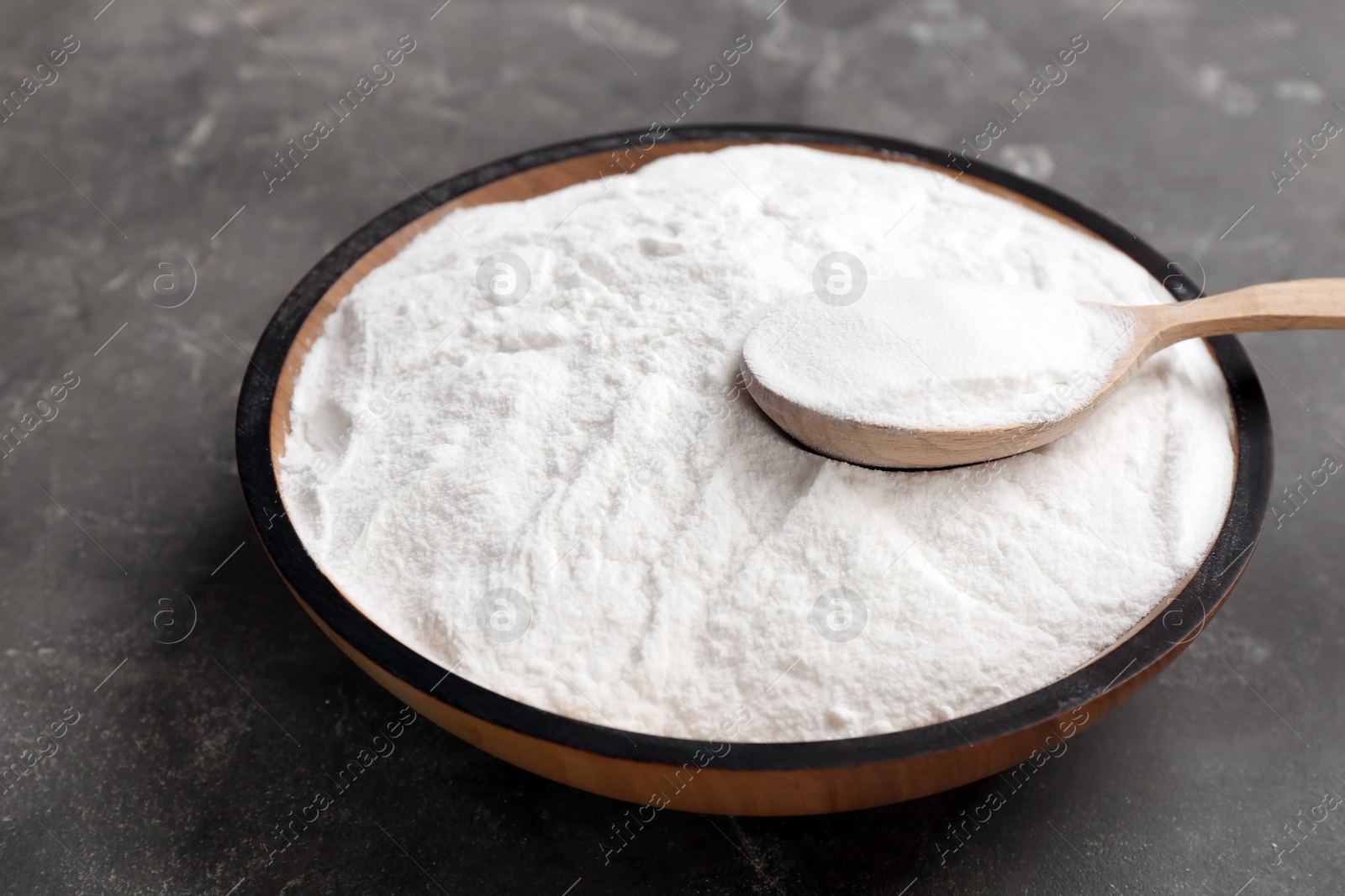 Photo of Bowl and spoon with baking soda on gray table