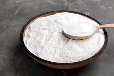 Photo of Bowl and spoon with baking soda on gray table