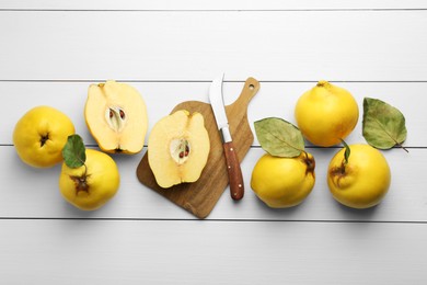 Tasty ripe quince fruits and knife on white wooden table, flat lay