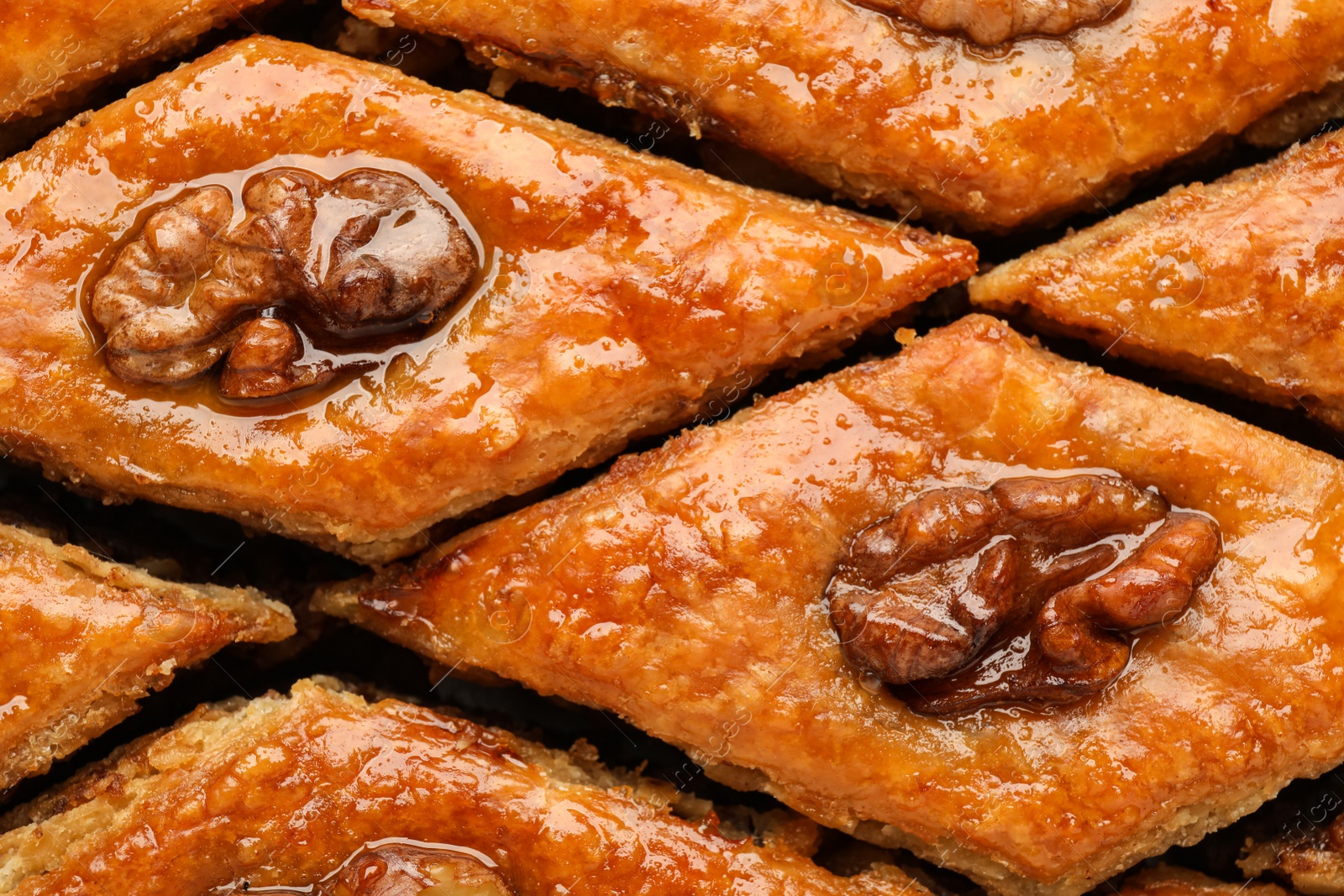 Photo of Delicious honey baklava with walnuts as background, top view