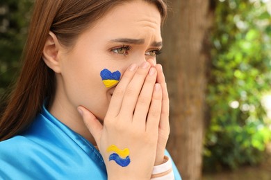 Photo of Emotional young Ukrainian woman with clasped hands outdoors, closeup. Space for text
