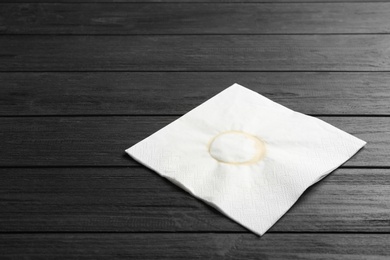 Photo of Paper napkin with coffee stain and space for text on wooden background