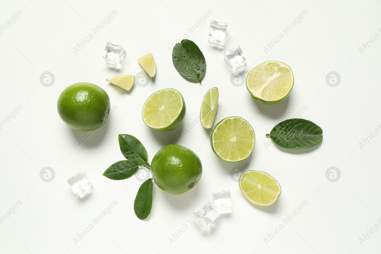 Photo of Fresh ripe limes with green leaves and ice cubes on white background, flat lay