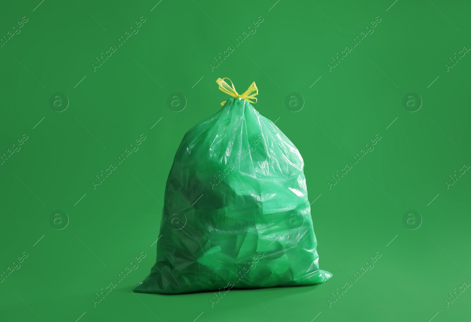 Photo of Trash bag full of garbage on green background