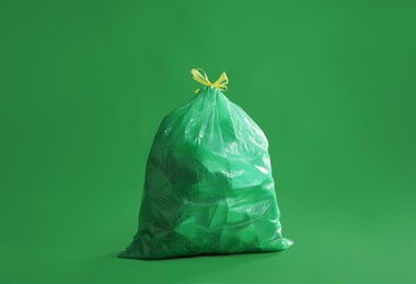 Trash bag full of garbage on green background