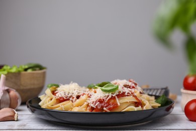 Photo of Delicious pasta with tomato sauce, basil and parmesan cheese on white wooden table