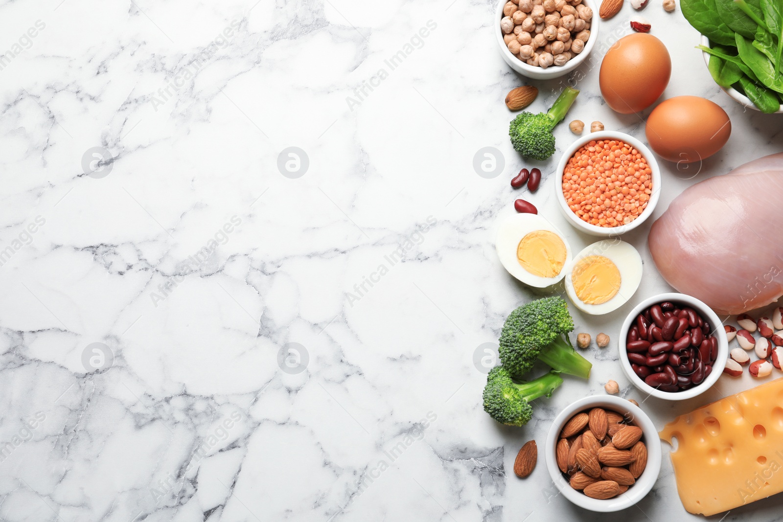 Photo of Set of natural food high in protein and space for text on marble background, top view