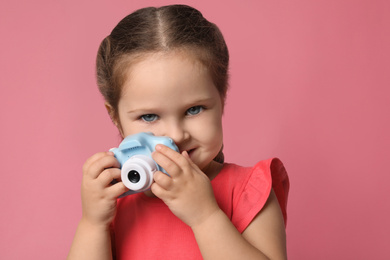 Photo of Little photographer with toy camera on pink background