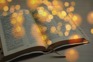 Image of Open Bible on wooden table, bokeh effect