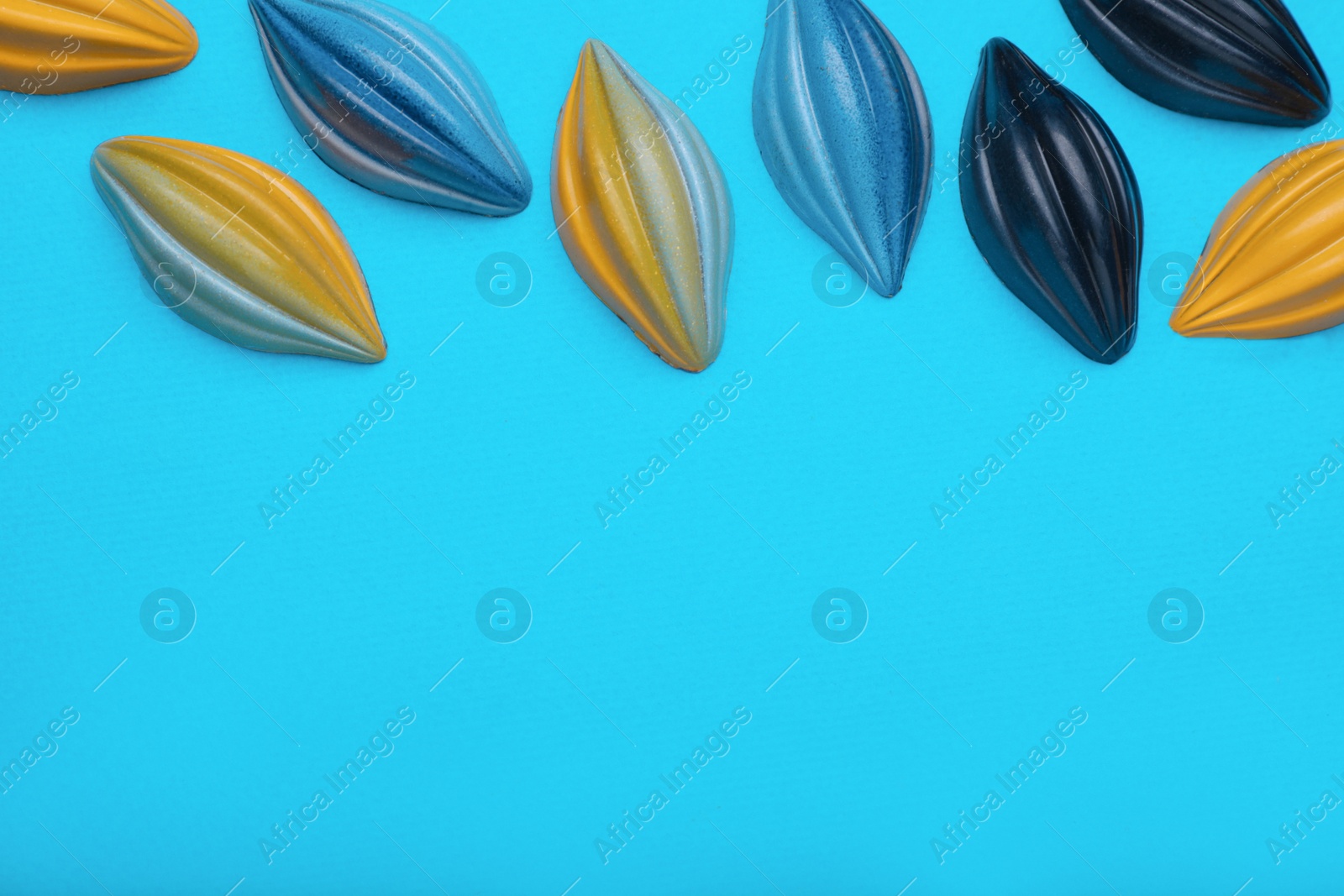 Photo of Tasty chocolate candies on light blue background, flat lay. Space for text