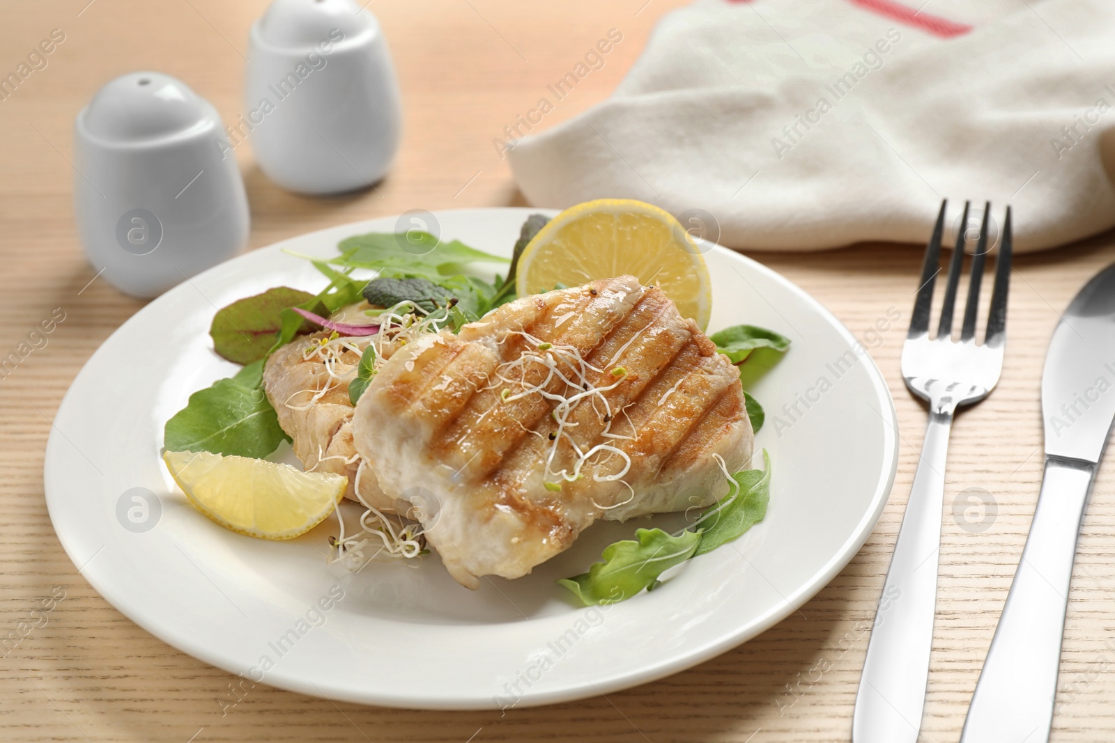 Photo of Tasty grilled fish served on wooden table, closeup