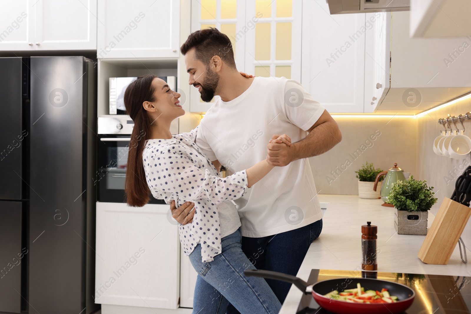 Photo of Lovely couple dancing together while cooking in kitchen