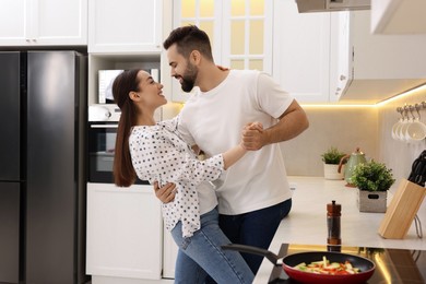 Lovely couple dancing together while cooking in kitchen