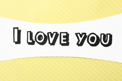 Photo of Card with text I Love You on yellow striped background, top view