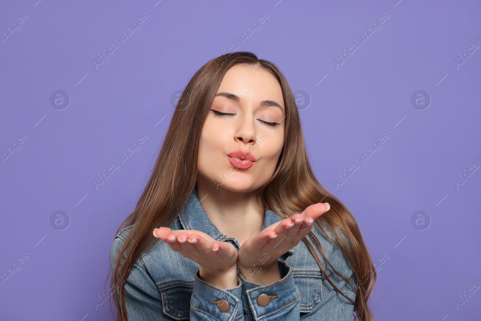 Photo of Beautiful young woman blowing kiss on purple background