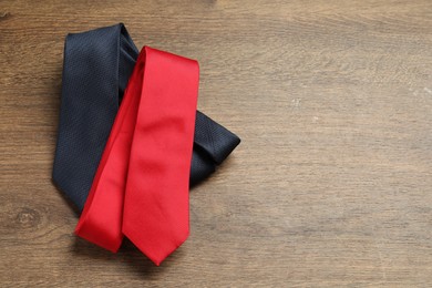 Photo of Red and blue neckties on wooden table, top view. Space for text