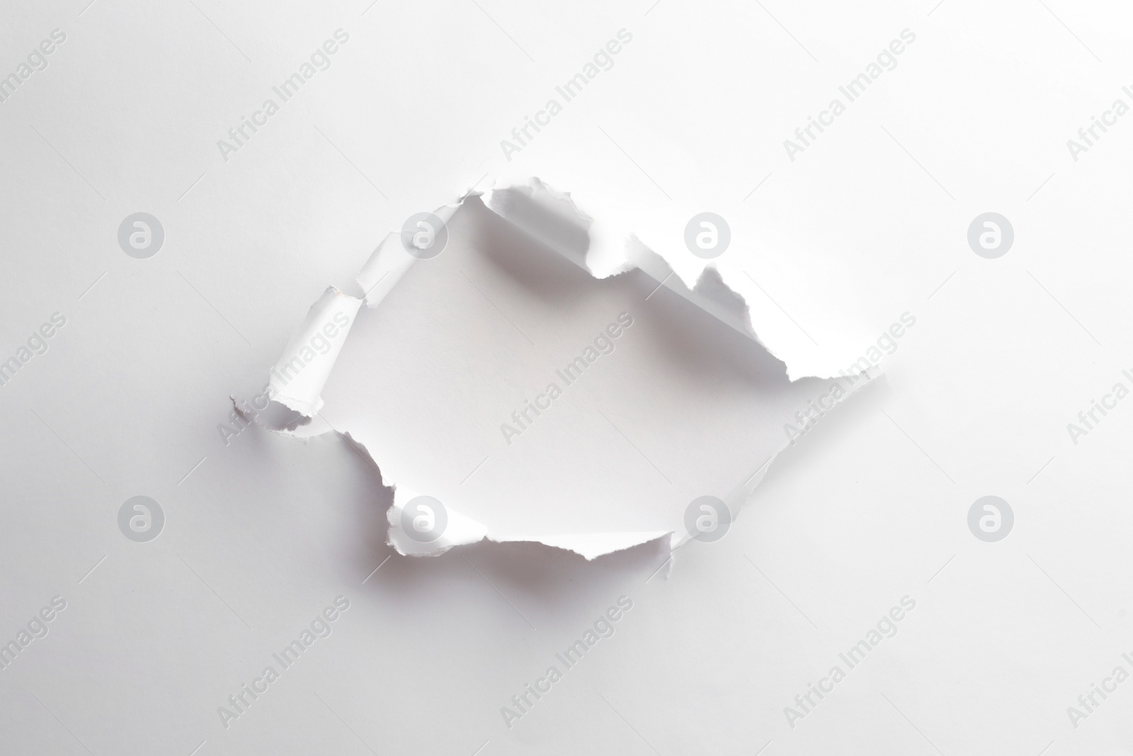 Photo of Hole in white paper on light background