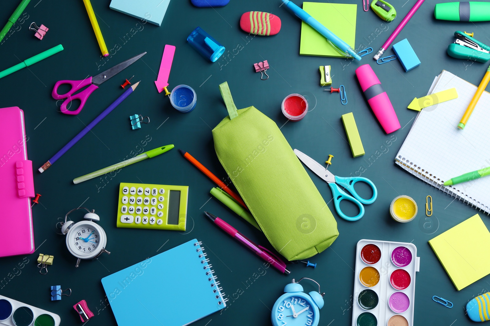 Photo of Different bright school stationery on green background, flat lay