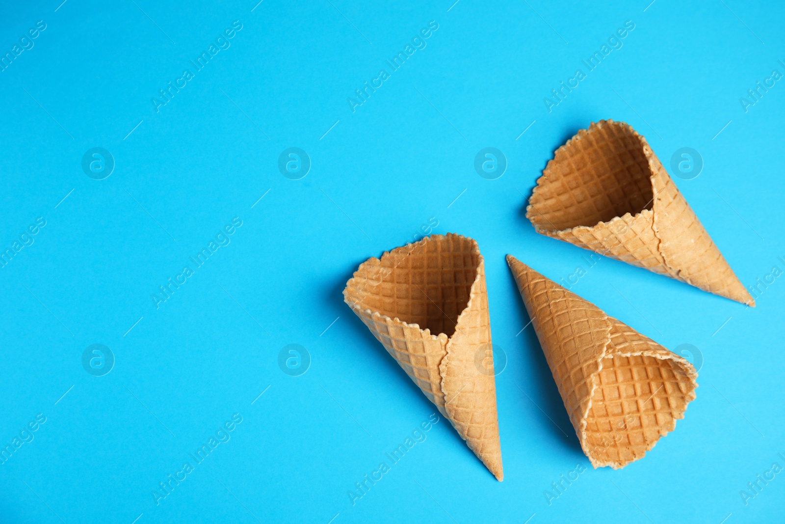 Photo of Waffle empty ice cream cones on color background, flat lay. Space for text