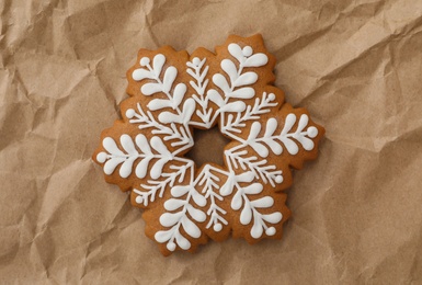 Photo of Christmas snowflake shaped gingerbread cookie on crumpled parchment, top view