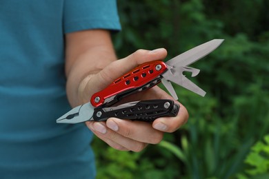 Man holding compact portable multitool outdoors, closeup