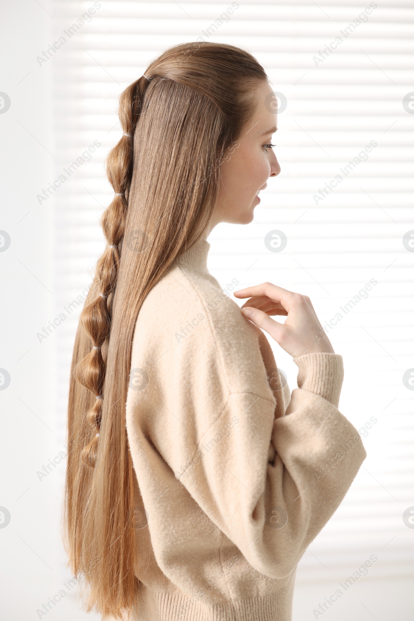 Photo of Young woman with long braided hair indoors