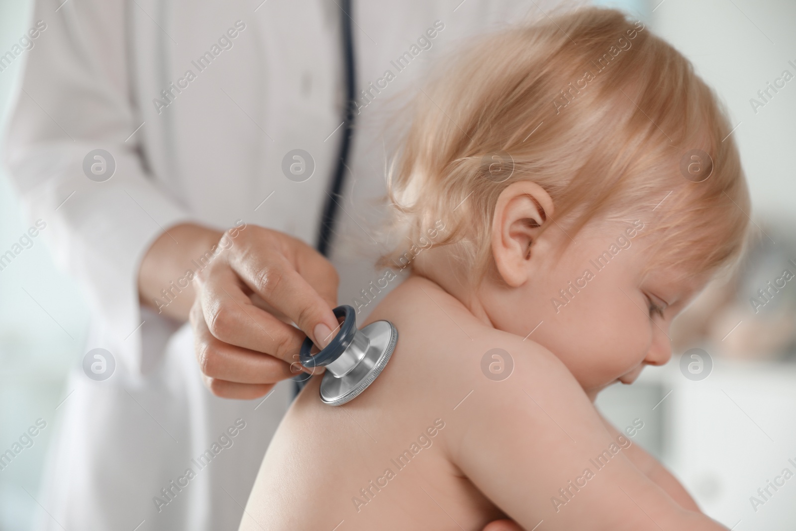 Photo of Pediatrician examining baby with stethoscope in hospital, closeup. Health care