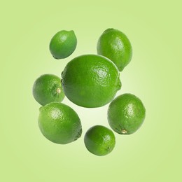 Image of Fresh lime fruits falling on light green background