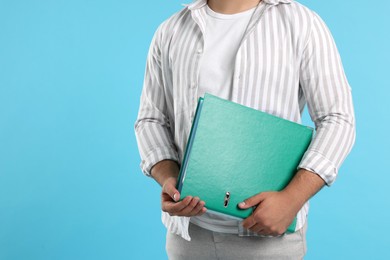 Photo of Man with folder on light blue background, closeup. Space for text