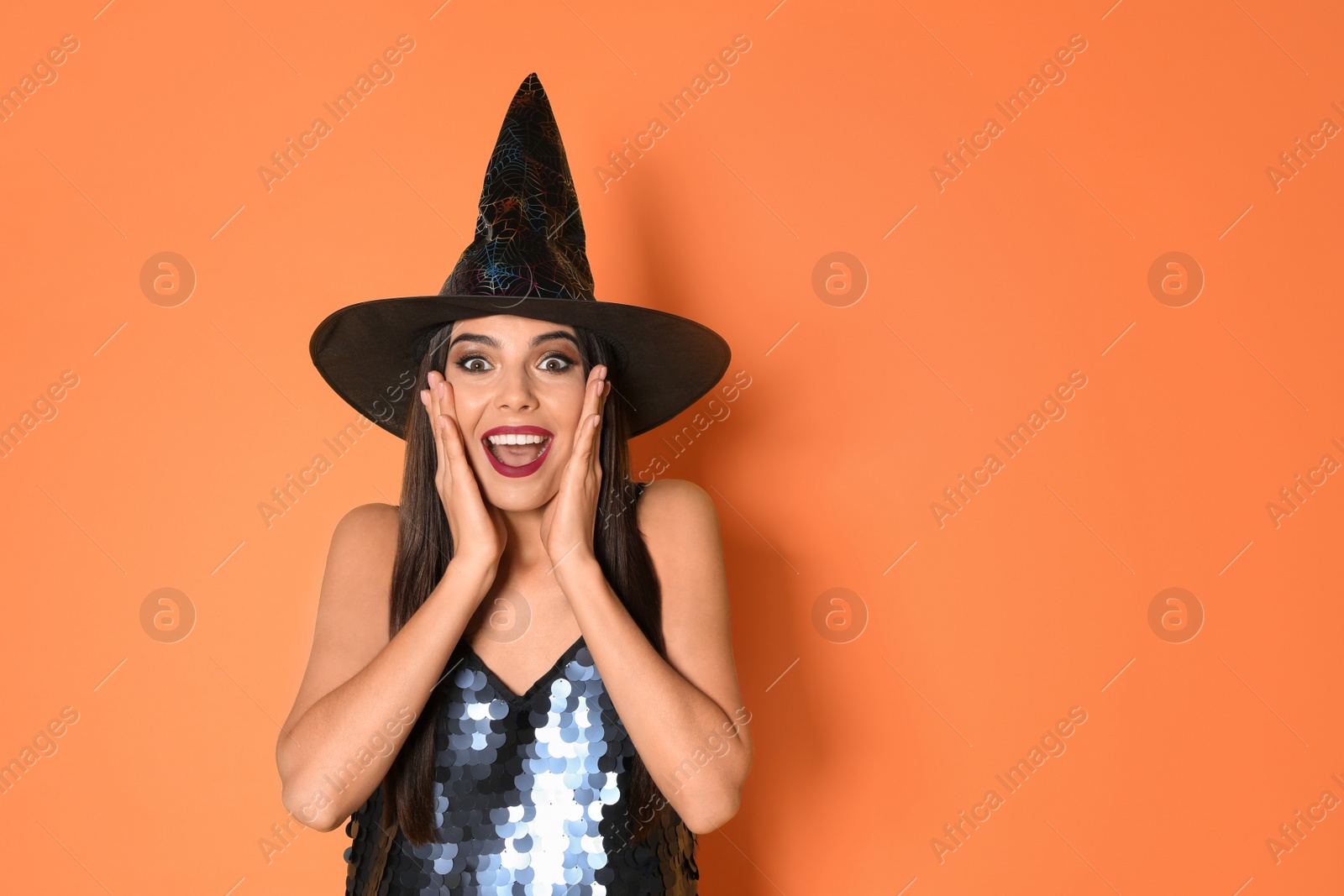 Photo of Excited woman wearing witch costume for Halloween party on yellow background, space for text