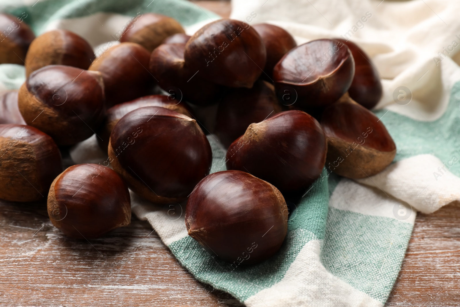 Photo of Sweet fresh edible chestnuts on wooden table, closeup