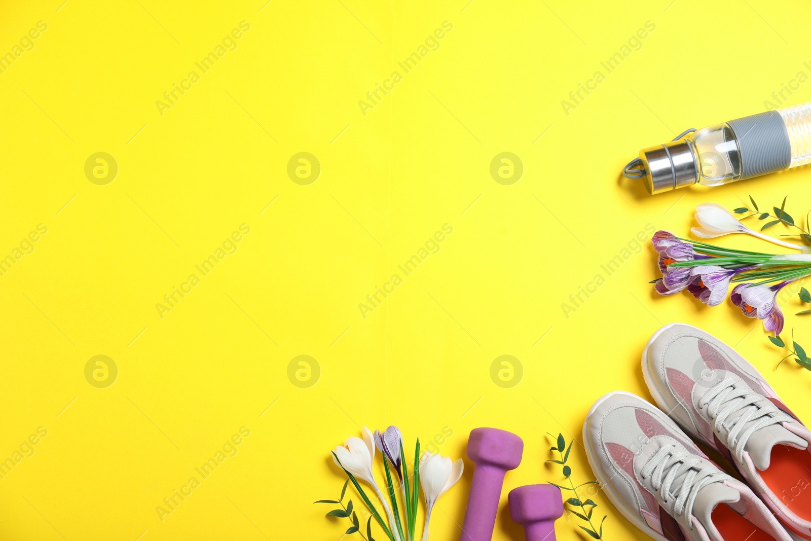 Photo of Flat lay composition with spring flowers and sports items on yellow background. Space for text