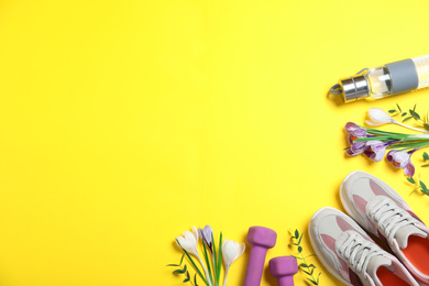 Photo of Flat lay composition with spring flowers and sports items on yellow background. Space for text