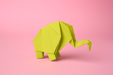 Photo of Origami art. Paper elephant on pink background