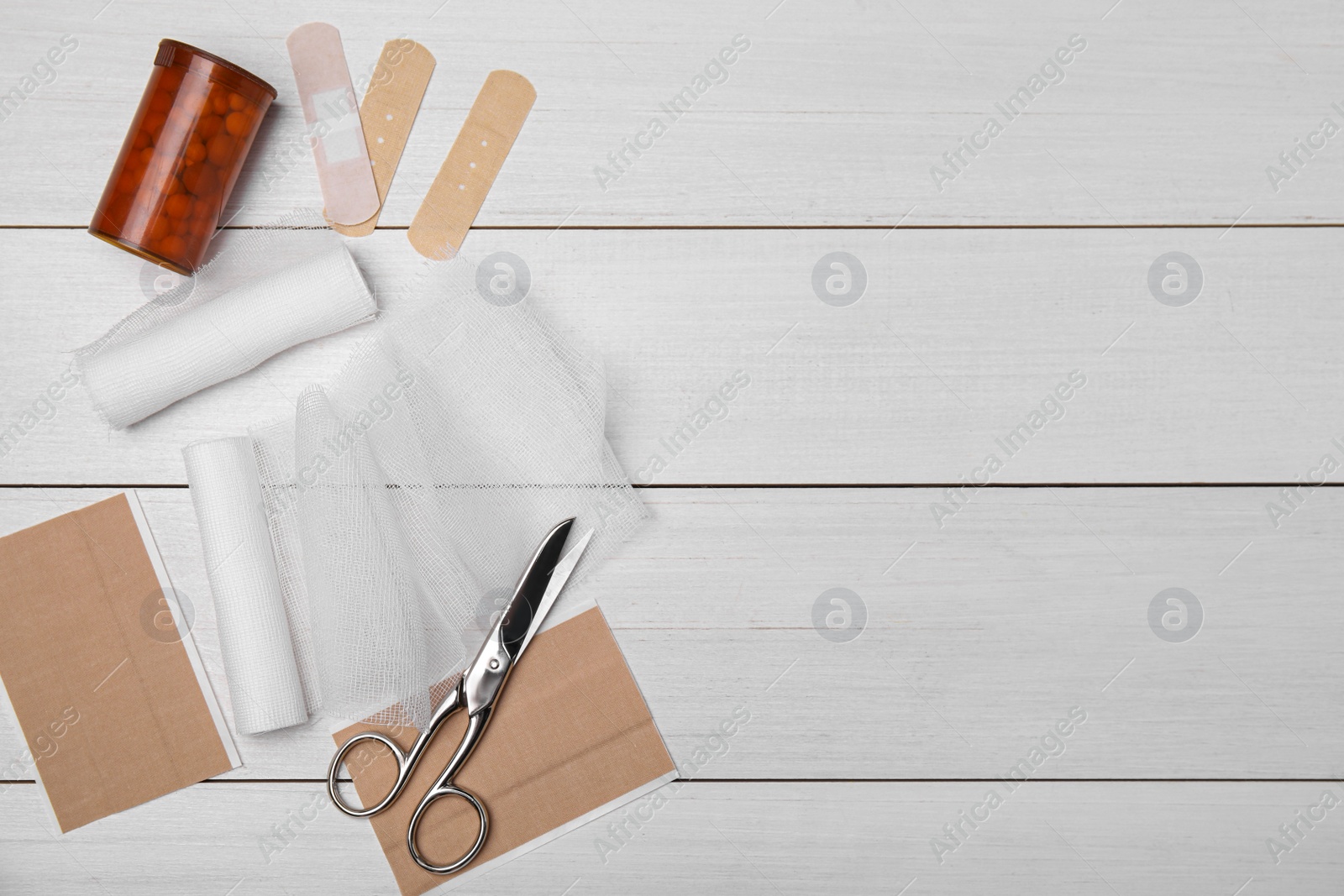Photo of Bandage rolls and medical supplies on white wooden table, flat lay. Space for text