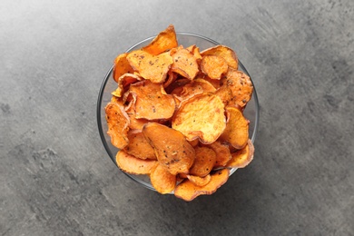 Photo of Bowl with sweet potato chips on grey table, top view
