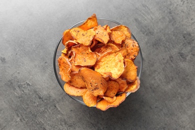 Bowl with sweet potato chips on grey table, top view