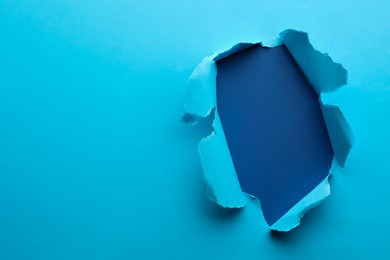 Hole in light blue paper on color background, space for text