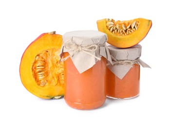 Photo of Jars of pumpkin jam and fresh pumpkin on white background