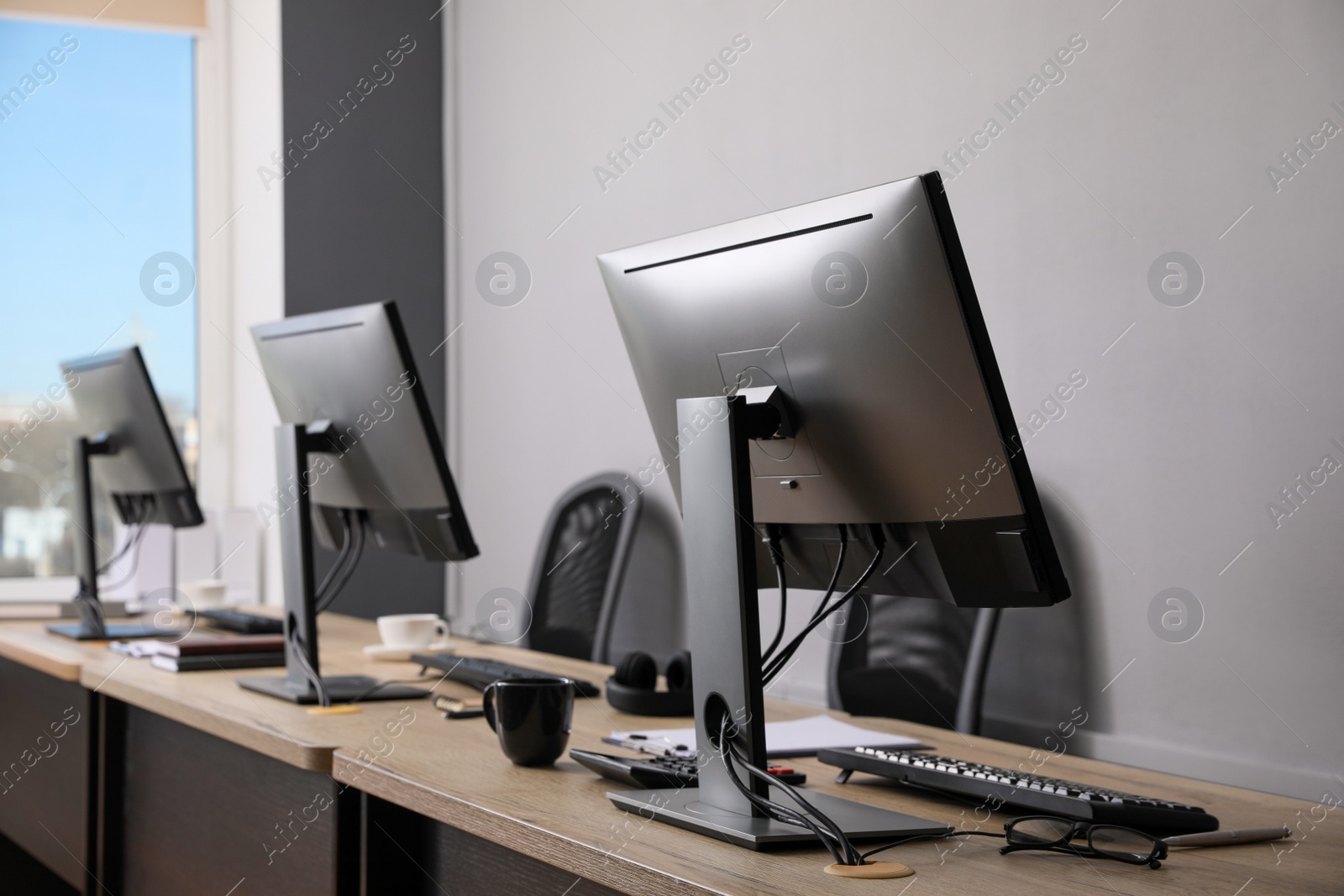 Photo of Open office interior. Modern workplaces with computers near light grey wall