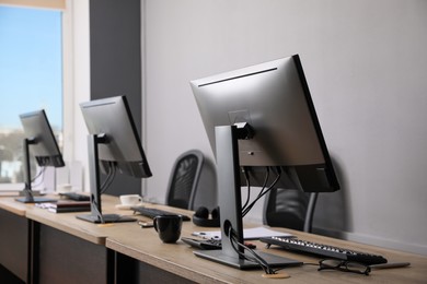 Open office interior. Modern workplaces with computers near light grey wall