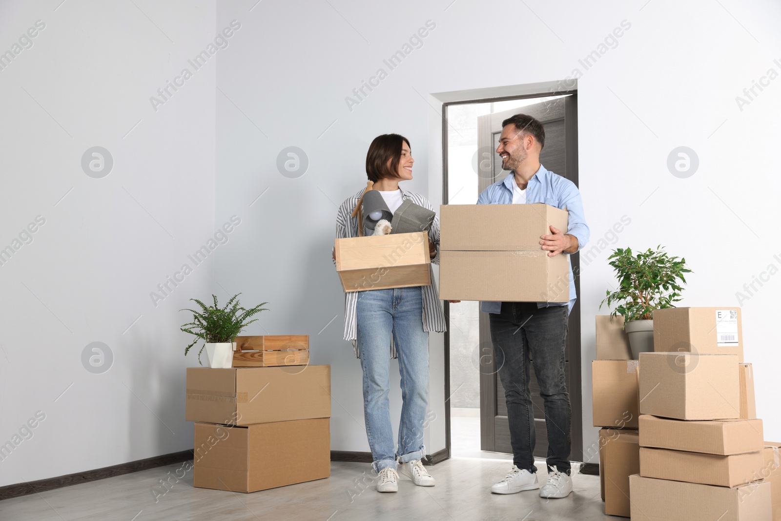 Photo of Happy couple with moving boxes entering in new apartment